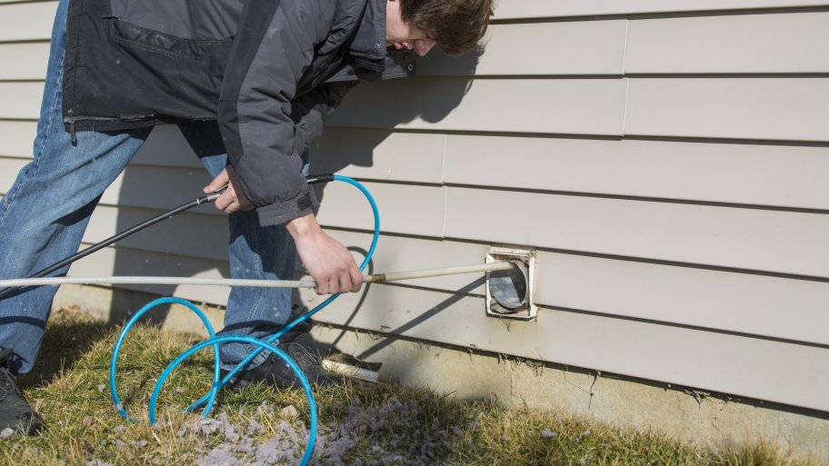 technician performing a dryer vent cleaning at a home